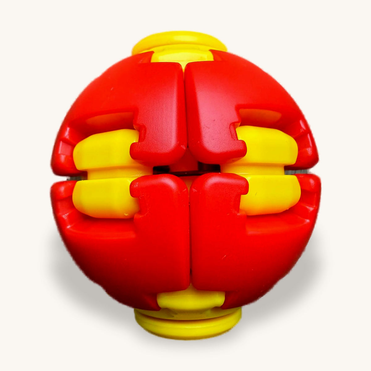 Red and yellow transforming fidget ball on a wooden table, segments interlocked