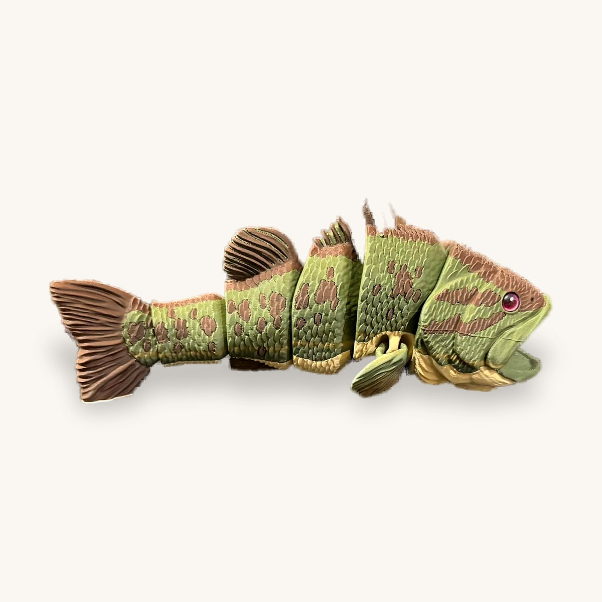 Green and brown 3D-printed articulated fish with segmented body and fanned tail on a plain background