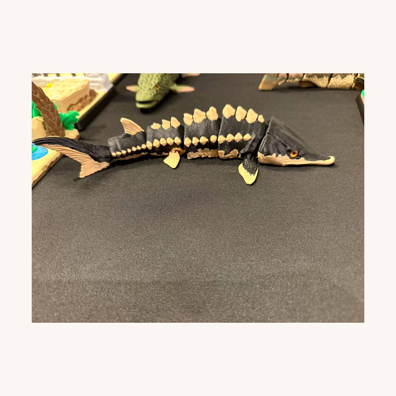 3D-printed articulated sturgeon, dark body with pale bony scutes along the back