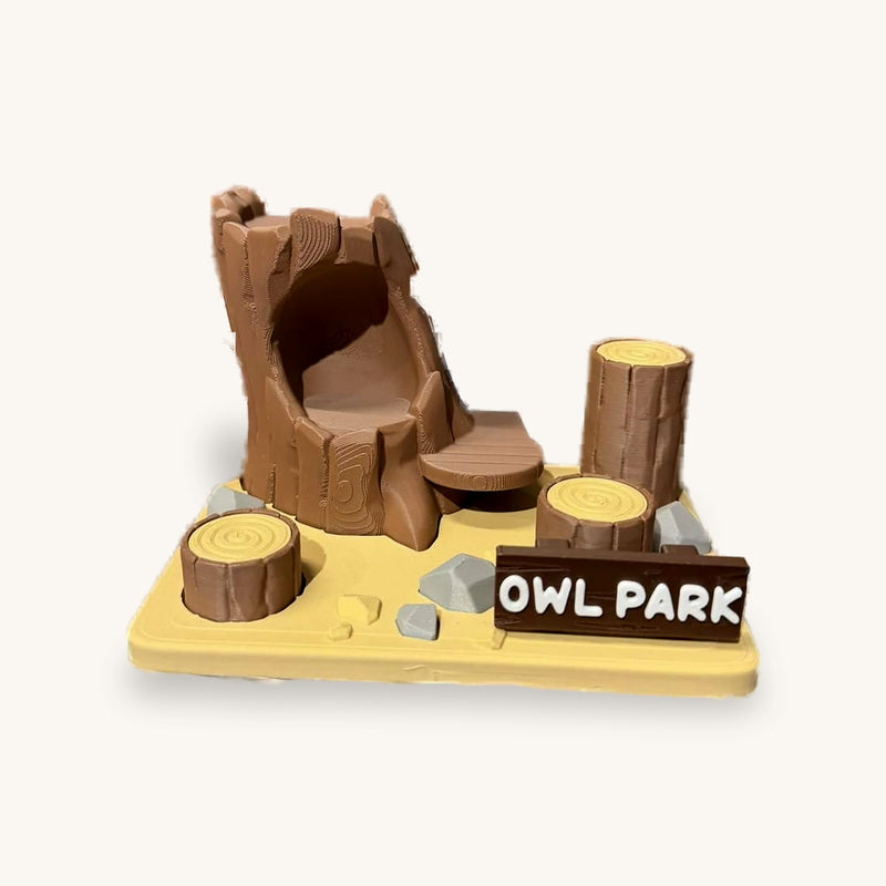 3D-printed miniature park scene with a hollow tree stump, log seats and an OWL PARK sign
