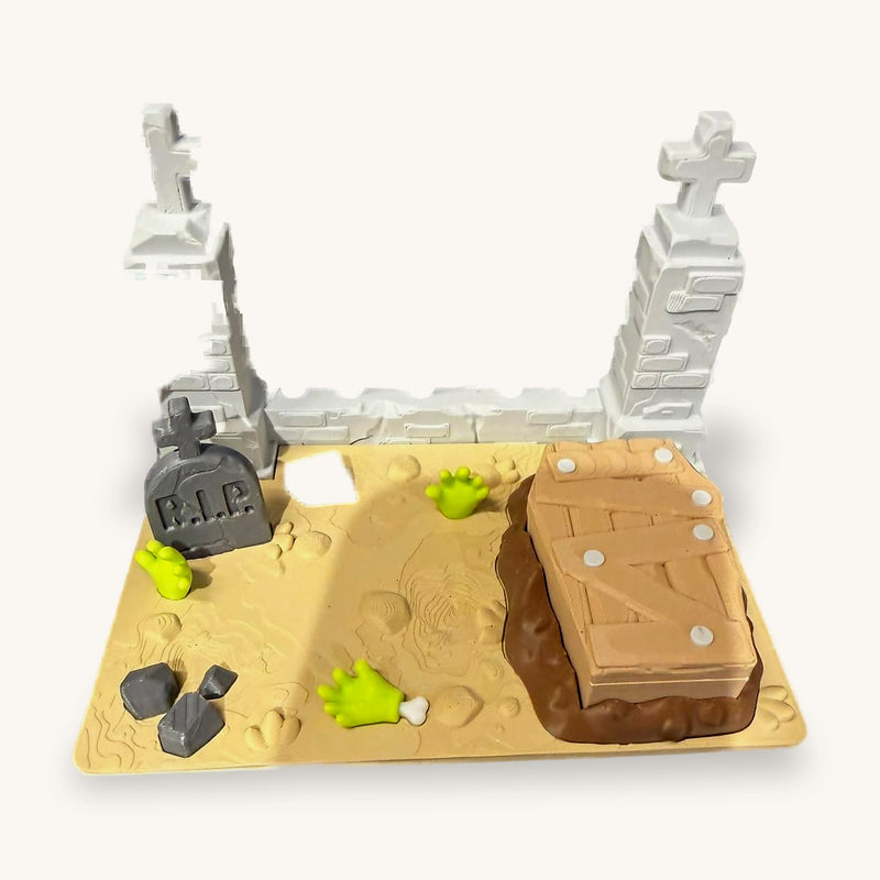 3D-printed miniature graveyard with a spiked fence, an R.I.P. headstone and an open coffin